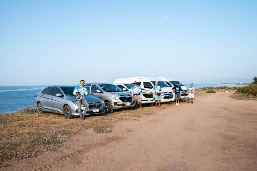 Local drivers stood by their vehicles in a row on the coast in Puerto Escondido